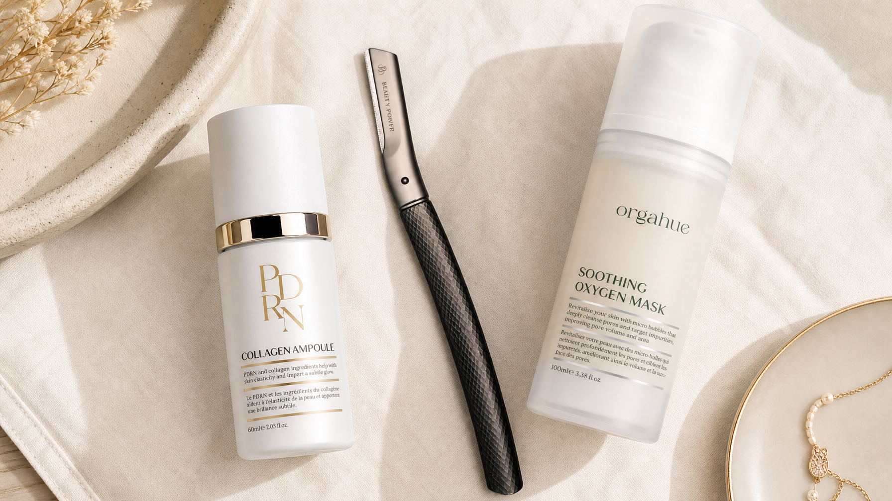 Beauty Power dermaplaning razor with knurled handle alongside Orgahue PDRN ampoule and Oxygen mask on cream linen