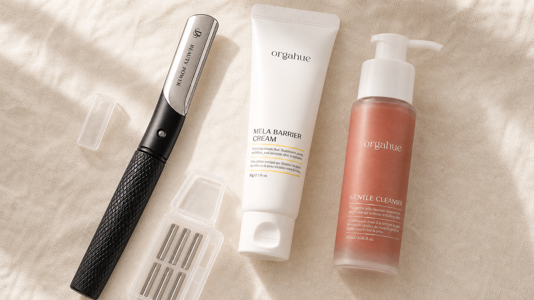 Beauty Power dermaplaning razor with silver head and matte black handle alongside Orgahue skincare on cream linen - Beauty Power dermaplaning and skincare prep guide