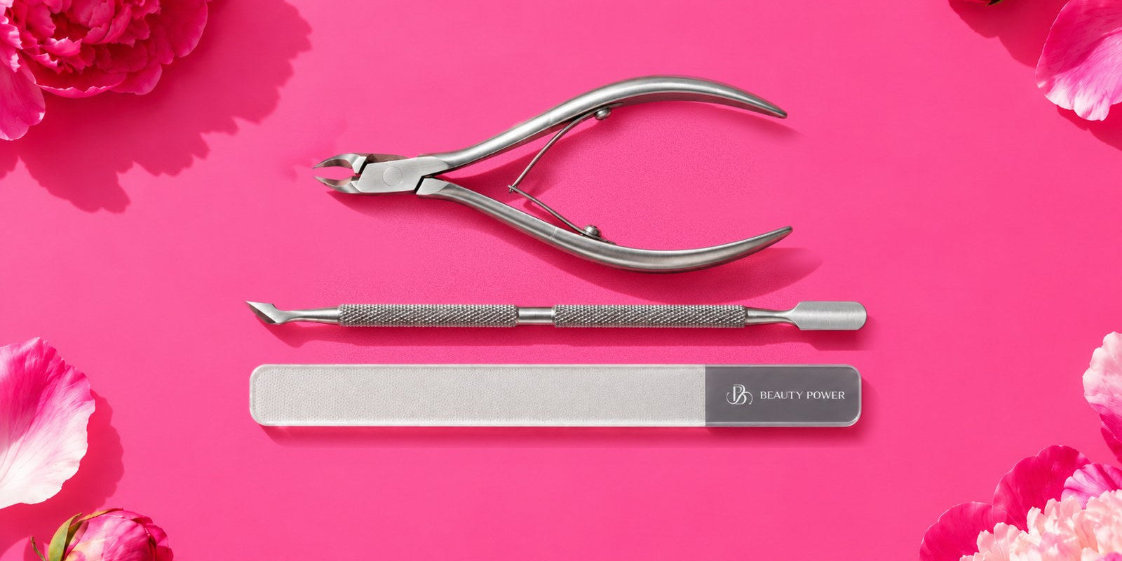 Beauty Power cuticle nippers, cuticle pusher and glass nail file on a hot pink backdrop with peonies