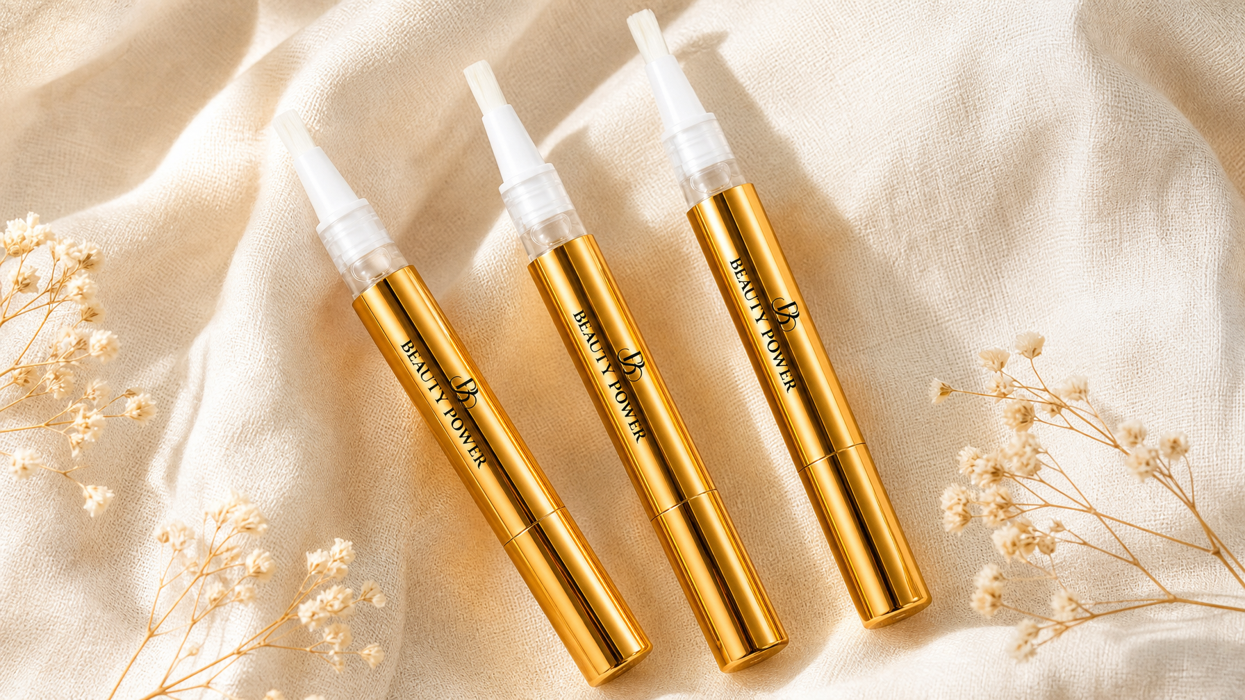 Beauty Power gold cuticle oil pens in strawberry, peach and watermelon on cream linen — cuticle oil benefits guide